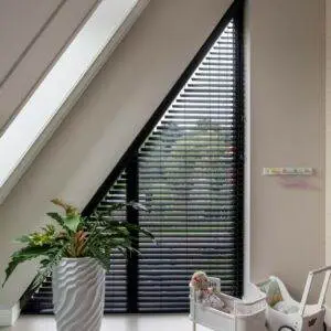Een kamer met zwarte jaloezieën op een zolder.